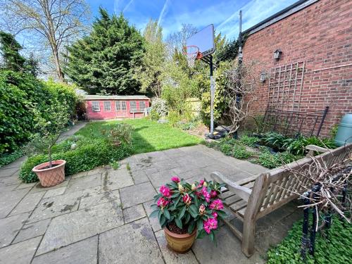 a garden with a wooden bench and some flowers at East Finchley N2 apartment close to Muswell Hill & Alexandra Palace with free parking on-site in London