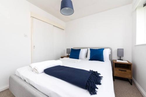 um quarto com uma grande cama branca com almofadas azuis em Beautiful House by Station with Private Parking em Cambridge