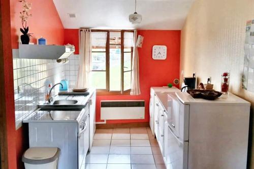 cocina con paredes rojas y electrodomésticos blancos en Appartement d'une chambre avec balcon et wifi a Mesnay, en Mesnay