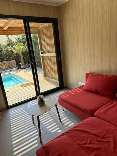 - un salon avec un canapé rouge et une piscine dans l'établissement Lo Spritz Grau d'Agde, au Grau-dʼAgde