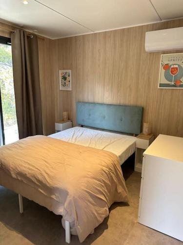 une chambre avec un grand lit avec une tête de lit bleue dans l'établissement Lo Spritz Grau d'Agde, au Grau-dʼAgde