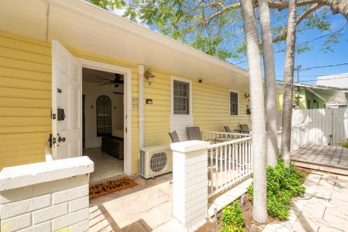 a yellow house with a porch and a white door at The Cozy Little Cottage in Key West