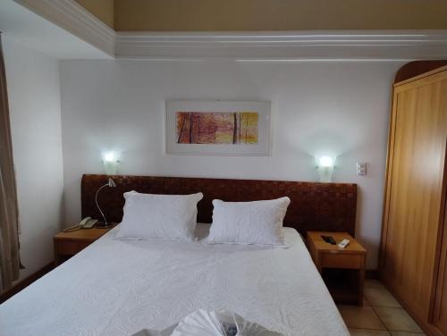 1 Schlafzimmer mit einem Bett mit weißer Bettwäsche und 2 Tischen in der Unterkunft Tropical Executive Hotel in Manaus