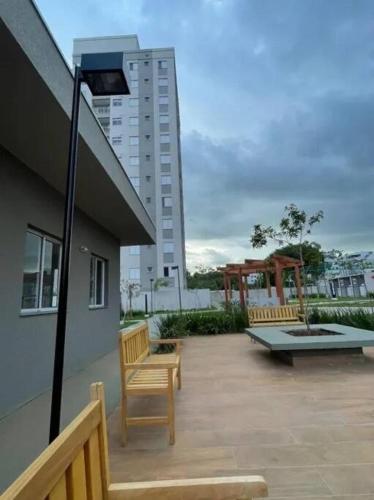 2 bancs assis sur une terrasse avec un bâtiment dans l'établissement Apartamento Oásis Itú, à Itu