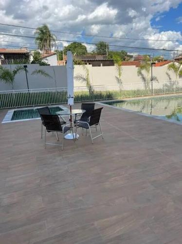 - une table et des chaises dans une cour avec une piscine dans l'établissement Apartamento Oásis Itú, à Itu