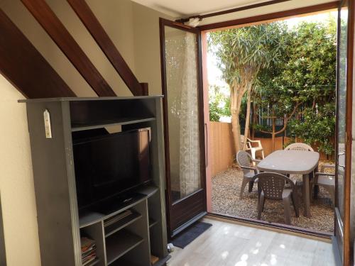 - un salon avec une télévision et une porte coulissante en verre dans l'établissement St Cyprien maison 4 personnes 200m de la plage, à Saint-Cyprien