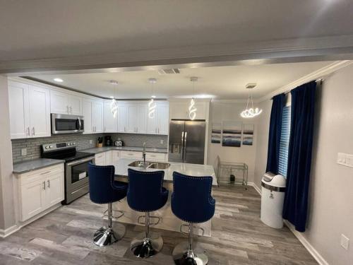 una cocina con armarios blancos y taburetes azules en Modern 3 bedrm 5 mins 2 airport free parking wi-fi en Kenner