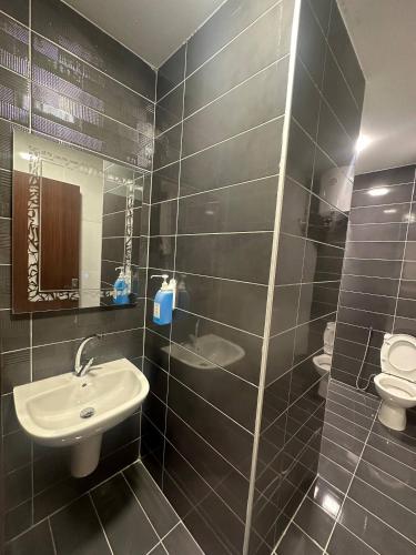 a black tiled bathroom with a sink and a toilet at Cozy and Tranquil Rooftop Near Al Services 23 in Amman