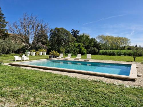 uma piscina num quintal com cadeiras à volta em Mas de la Sorgue - Rendez-vous en Provence em Bédarrides