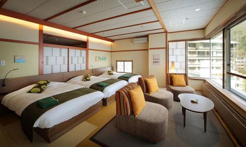 um quarto de hotel com duas camas e um sofá em Sakunami Onsen Yuzukushi Salon Ichinobo em Sendai