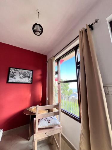 a room with a red wall and a window at The Hostel Stories Dharamkot - Mcleodganj in McLeod Ganj