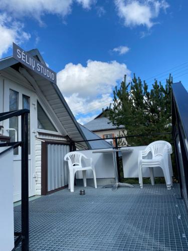 two white chairs sitting on top of a building at „Sėlių Studio“ Apartamentai in Utena