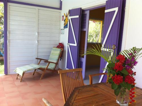 a porch with a table and chairs and a door at Au Village de Menard in Saint-Louis