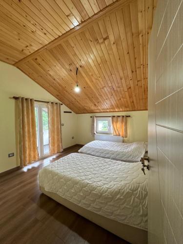 Cama grande en habitación con techo de madera en Guest House Artjon, en Fierzë
