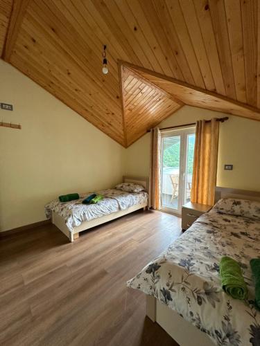 een slaapkamer met 2 bedden en een houten plafond bij Guest House Artjon in Fierzë