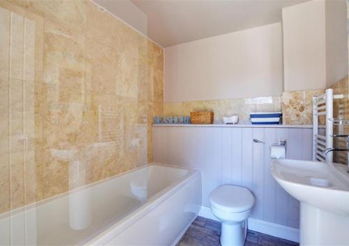 a bathroom with a tub and a toilet and a sink at Hawthorne and Rainbow Cottage in Roughton