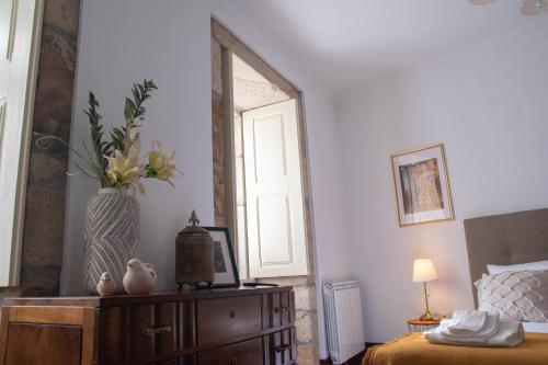 a bedroom with a vase of flowers on a dresser at Cosy Historical House in Lamego - Quinta do Cabo in Lamego