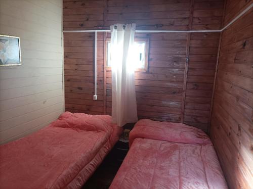 two beds in a small room with a window at Complejo Nueva Luna in La Coronilla