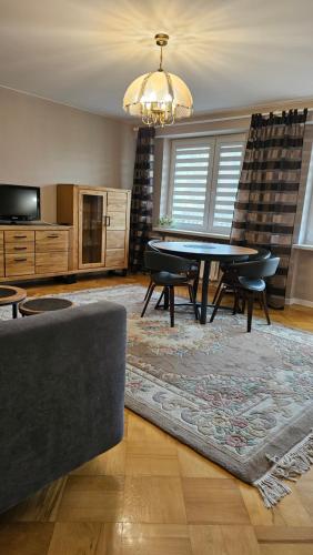 ein Wohnzimmer mit einem Tisch, Stühlen und einem Kronleuchter in der Unterkunft Apartament na Kazańskiej in Łomża