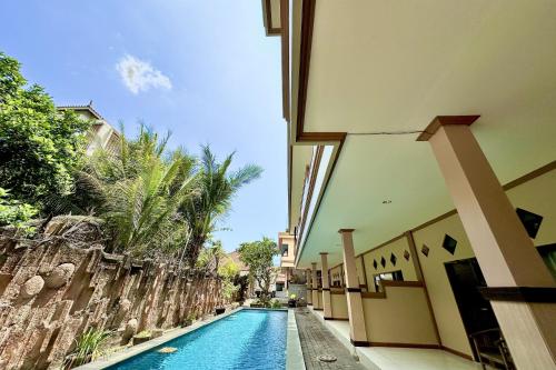 a swimming pool in the middle of a building at Taxa Raya Guest House in Legian