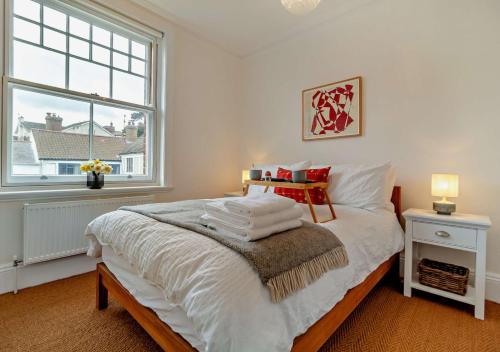 een slaapkamer met een bed met witte lakens en een raam bij Heritage Retreat - Aldeburgh in Aldeburgh