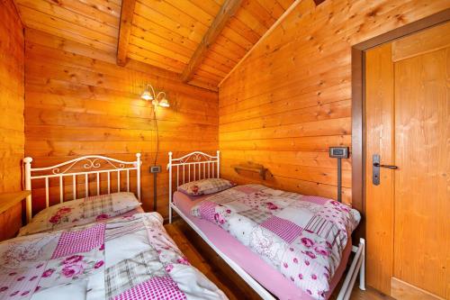 two beds in a log cabin with wooden walls at Orserose Chalet 6 I Scarpet in Forno di Zoldo