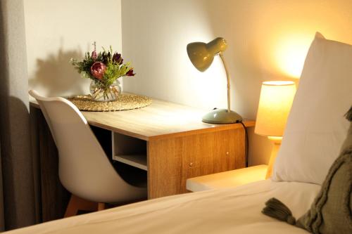 een slaapkamer met een bureau en een vaas met bloemen bij Woodlea self-catering flatlet in Pringle Bay