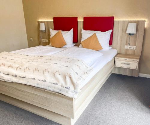 Cama grande con sábanas y almohadas rojas y blancas en Hotel Garni Silvana en Sankt Peter-Ording