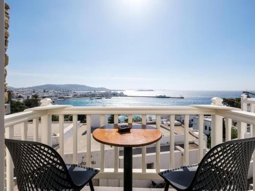 a table on a balcony with a view of the ocean at Yalos Hotel Sunset view Mykonos town private rooms in Mikonos