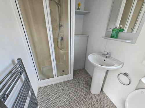 baño blanco con ducha y lavamanos en Golden sands, en Rhyl