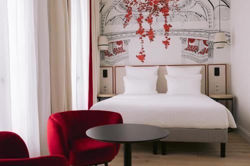 a bedroom with a bed and a table and a chair at Hôtel Majestic in Bordeaux