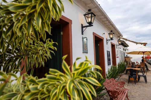 a building with a patio with chairs and an umbrella at Pousada Do Largo in Tiradentes