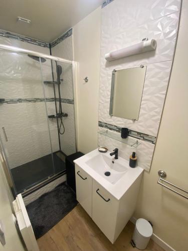 a white bathroom with a sink and a shower at Les Bruyères in Martigues