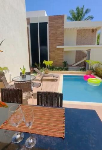 a patio with a pool and two wine glasses on a table at Vilagem tulum barra grande 2 quartos piscina in Marau