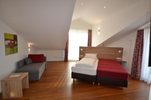 a small bedroom with a bed and a couch at Weinhaus Steppe Hotel 3***Superior und Weinstube in Waldbronn