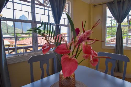 a vase with flowers on a table in a dining room at Apartment Soleil- Because Location really is everything! in Soufrière