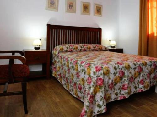 1 dormitorio con 1 cama con colcha de flores y silla en Casa para Familias con piscina y Barbacoa, en Conil de la Frontera
