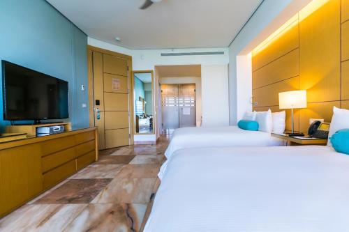 a hotel room with two beds and a flat screen tv at Palacio Mundo Imperial Riviera Diamante Acapulco All Inclusive in Acapulco