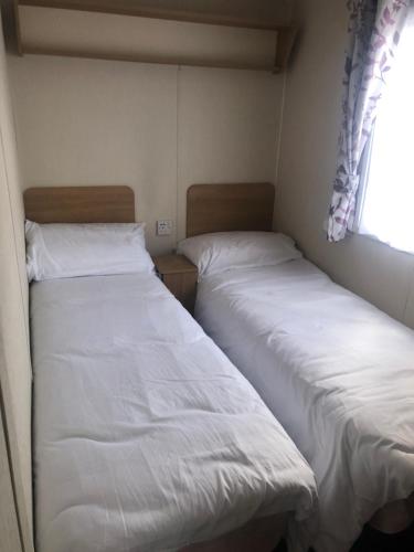 2 camas en una habitación pequeña con ventana en Rockley Park, en Lytchett Minster