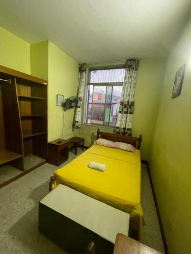 Un dormitorio con una cama amarilla y una ventana en HOSPEDAJE GRAN PAJATEN, en Tarapoto