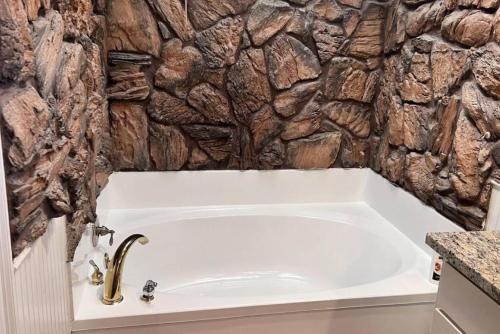 a bath tub in a bathroom with a stone wall at Pool/ Outdoor kitchen/Pool table in Houston