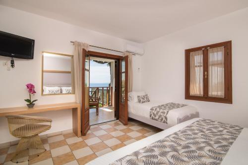 a bedroom with a bed and a desk and a television at Sea View Village in Vasilikos