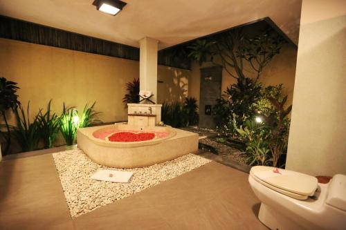 a bathroom with a bath tub and a toilet at The Sanyas Suite Bali in Seminyak