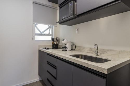 a kitchen counter with a sink and a window at Duque by My Way - a 100 metros da Santa Casa e UFRGS in Porto Alegre