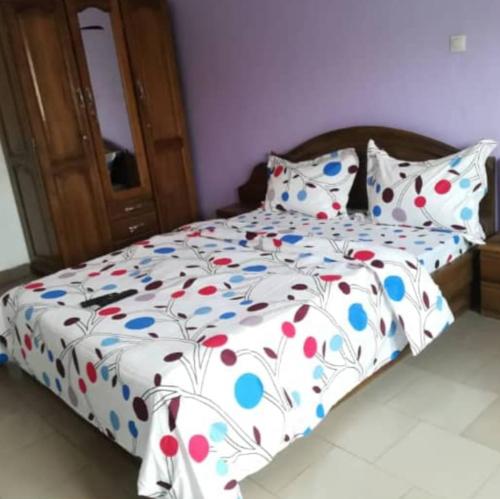 a bed with a white comforter with colorful pillows at Résidences la Diaspora in Yaoundé