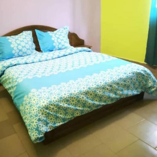 a bed with a blue comforter and blue pillows at Résidences la Diaspora in Yaoundé