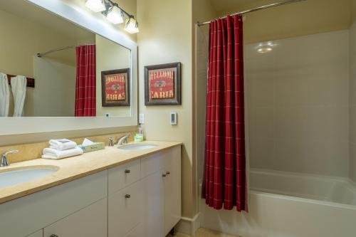 a bathroom with two sinks and a shower with a red shower curtain at Evergreen Condo 26 in Ketchum