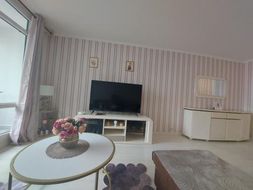 Una sala de estar con un televisor y una mesa. en Logement avec parking à 11 min de Paris et 15 min de la défense Arena, en Argenteuil