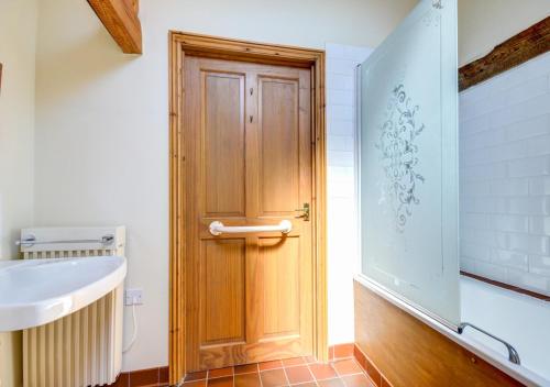 a bathroom with a wooden door and a sink at Pond Cottage in Sidestrand