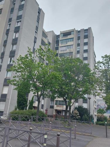 dos árboles frente a dos edificios altos en Logement avec parking à 11 min de Paris et 15 min de la défense Arena, en Argenteuil